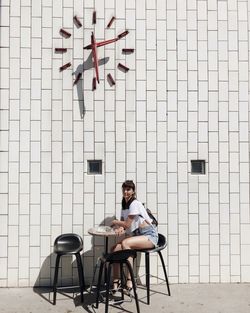 Man sitting on chair against wall