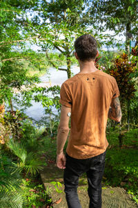 Rear view of boy standing against trees