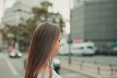 Side view of young woman standing on street in city