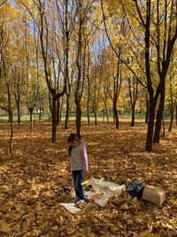 Full length of girl standing by garbage amidst autumn leaves