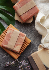 Assorted handmade soap bars, towels and green leaves on concrete background