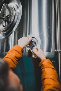 Cropped hands of male worker filling glass with beer at distillery