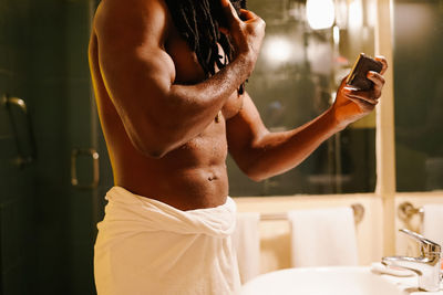 Midsection of shirtless man in bathroom at home