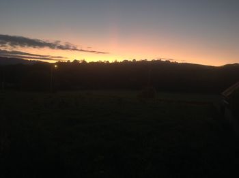 Scenic view of silhouette field against sky during sunset