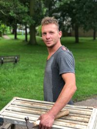 Portrait of man with hammer at park bench