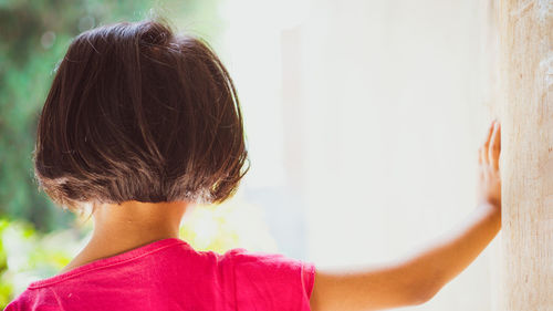 Rear view of girl standing by wall