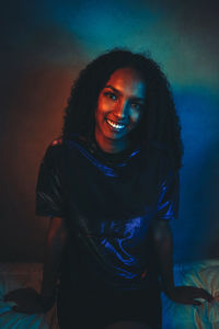 Portrait of smiling young woman sitting on bed