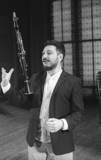 Man holding clarinet while standing at studio