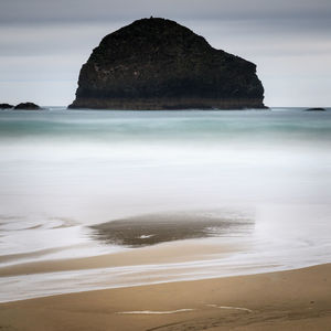 Rock formation on beach against sky