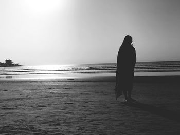 Rear view of silhouette man on beach against sky