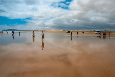 Group of people on beach against sky