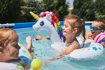 Children playing in a pool in a home garden. kids having fun playing together on a summer sunny day