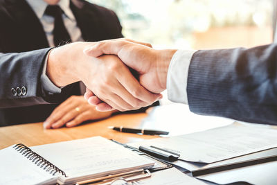 Midsection of man and woman holding hands on table