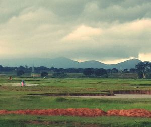 Scenic view of grassy field against cloudy sky