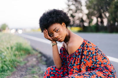 Portrait of young woman sitting by road