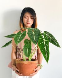 Portrait of woman with potted plant against white background