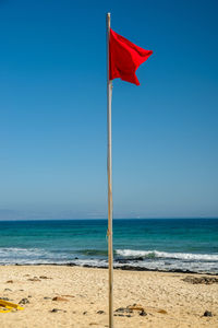 Flag on beach against blue sky