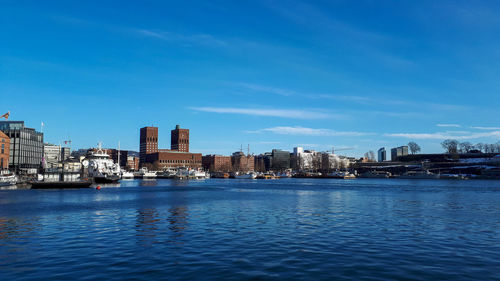 Sea by buildings against blue sky