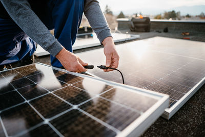 Midsection of man installing solar panel on roof