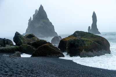 Rock formations on beach against sky