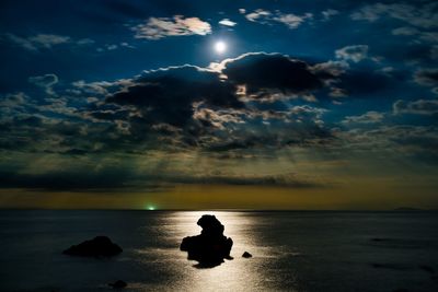 Silhouette people on sea against sky during sunset