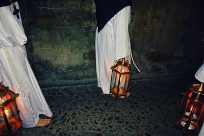 Low section of man standing by illuminated lamp