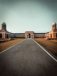 Road leading towards buildings against sky in city