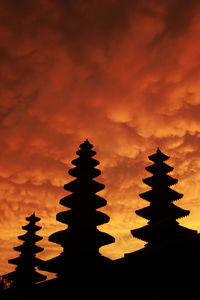 Silhouette of temple against cloudy sky during sunset