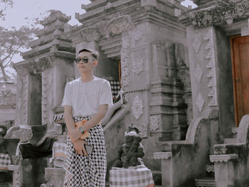 Man wearing sunglasses standing against temple