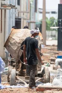 Rear view of man working on street in city