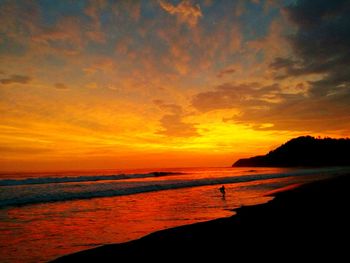 Scenic view of sea against dramatic sky during sunset