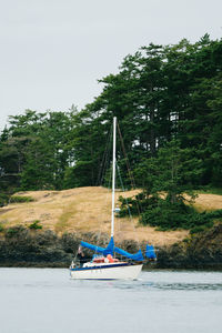 Sailboat moored on riverbank against sky