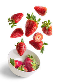 Strawberries flying in white bowl isolated from the background