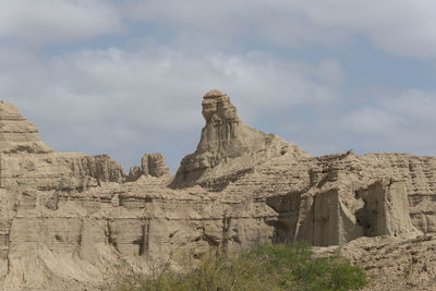 Rock formations on mountain against cloudy sky