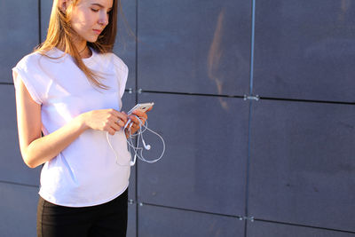 Portrait of young woman standing against wall