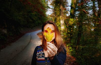 Portrait of person holding umbrella standing by trees in forest