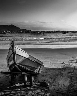 Abandoned boat on beach against sky