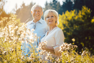 Senior couple standing side by side on a meadow in the sunshine