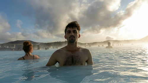 Portrait of young man in swimming pool against sky