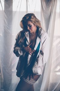 Young woman standing against curtain