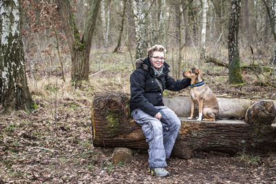 Full length portrait of man with dog standing in forest