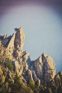 Rock formations by sea against clear sky