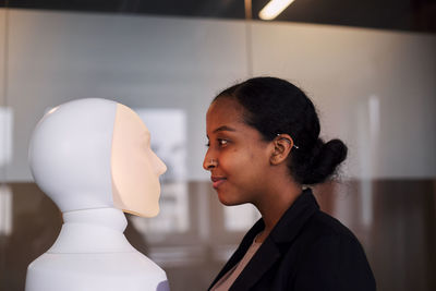 Young woman looking at robot voice assistant