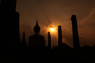 Silhouette statue against sky at sunset