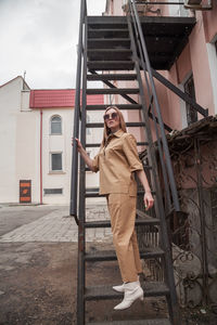 Full length outside portrait of fashion model in sunglasses, beige summer spring suit in urban area