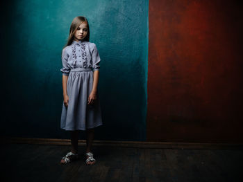 Portrait of smiling girl standing against wall