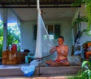 Young man sitting against built structure