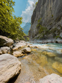 Rocks by river against sky