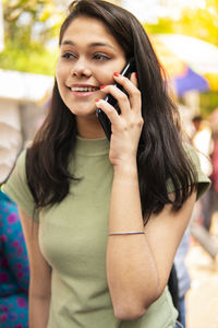 Portrait of smiling young woman using mobile phone