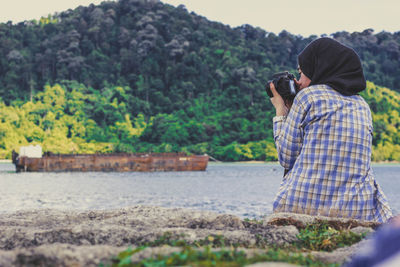 Rear view of couple photographing against trees